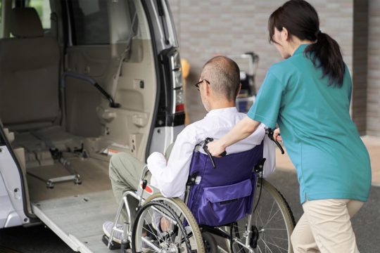 Caregiver helping an elderly person into a taxi