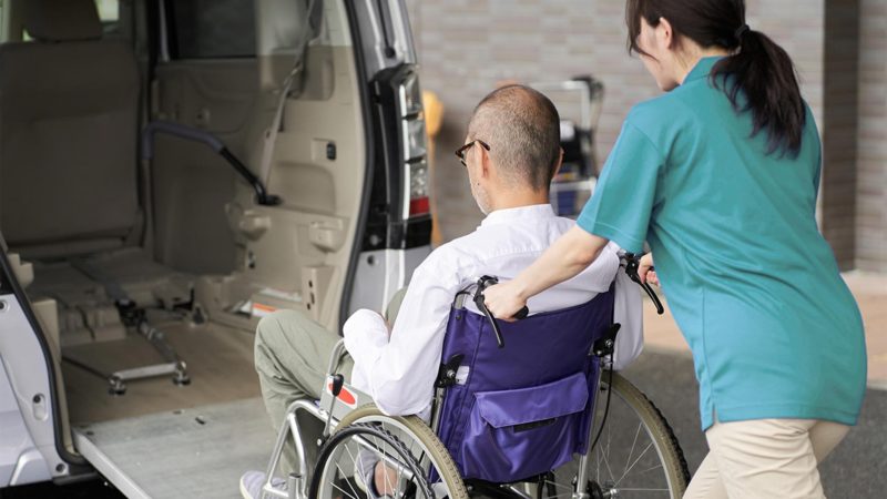 Caregiver helping an elderly person into a taxi