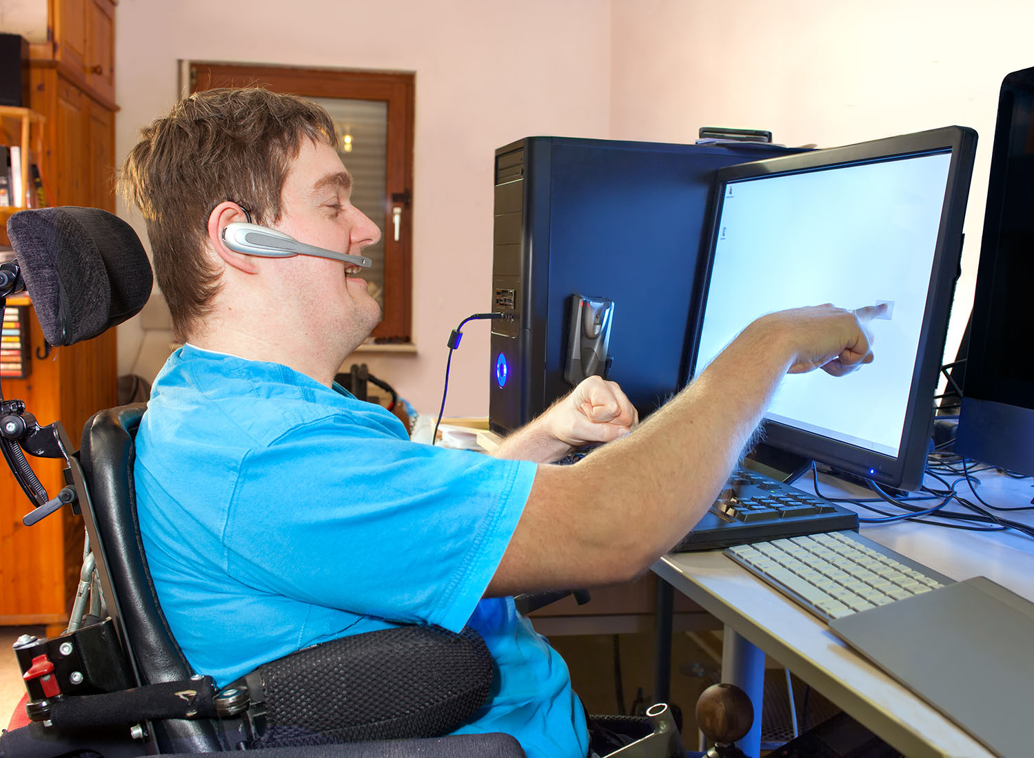a young man with cerebral palsy sitting using touch screen computer