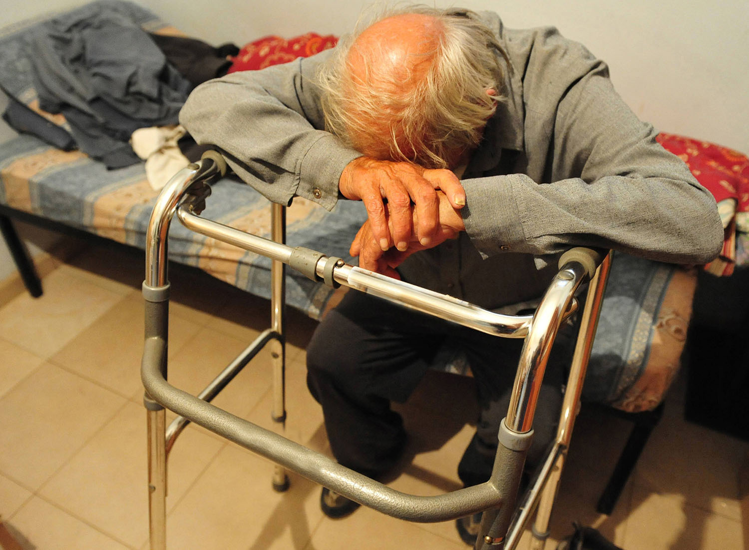 elderly man sitting alone on his bed.
