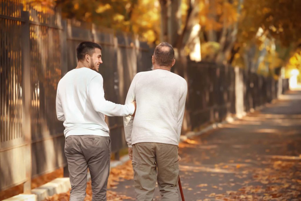 young caregiver with elderly man in park