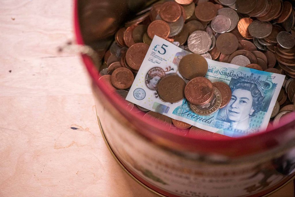 UK currency coins and notes in a pot