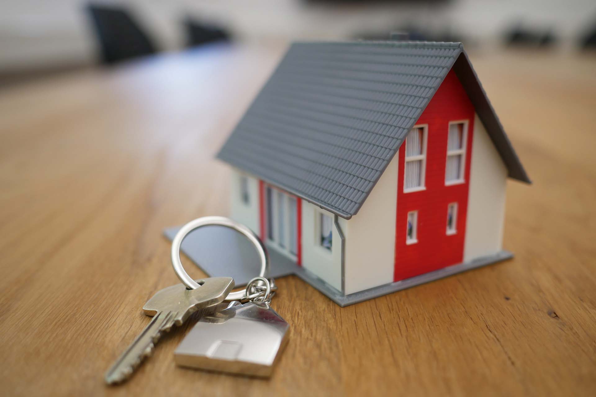 House keys on desk next to toy house