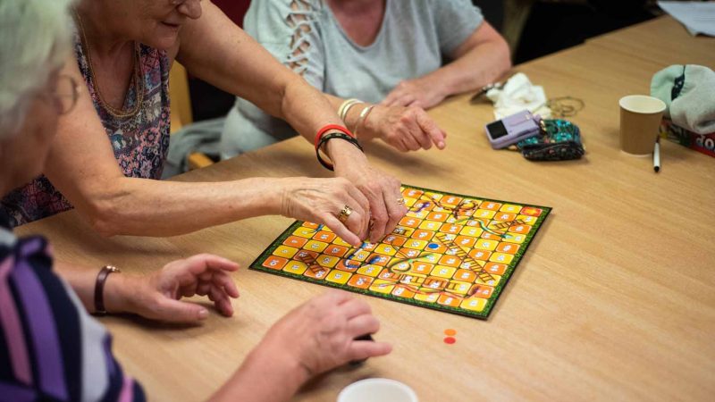 three People playing board game in care environment.