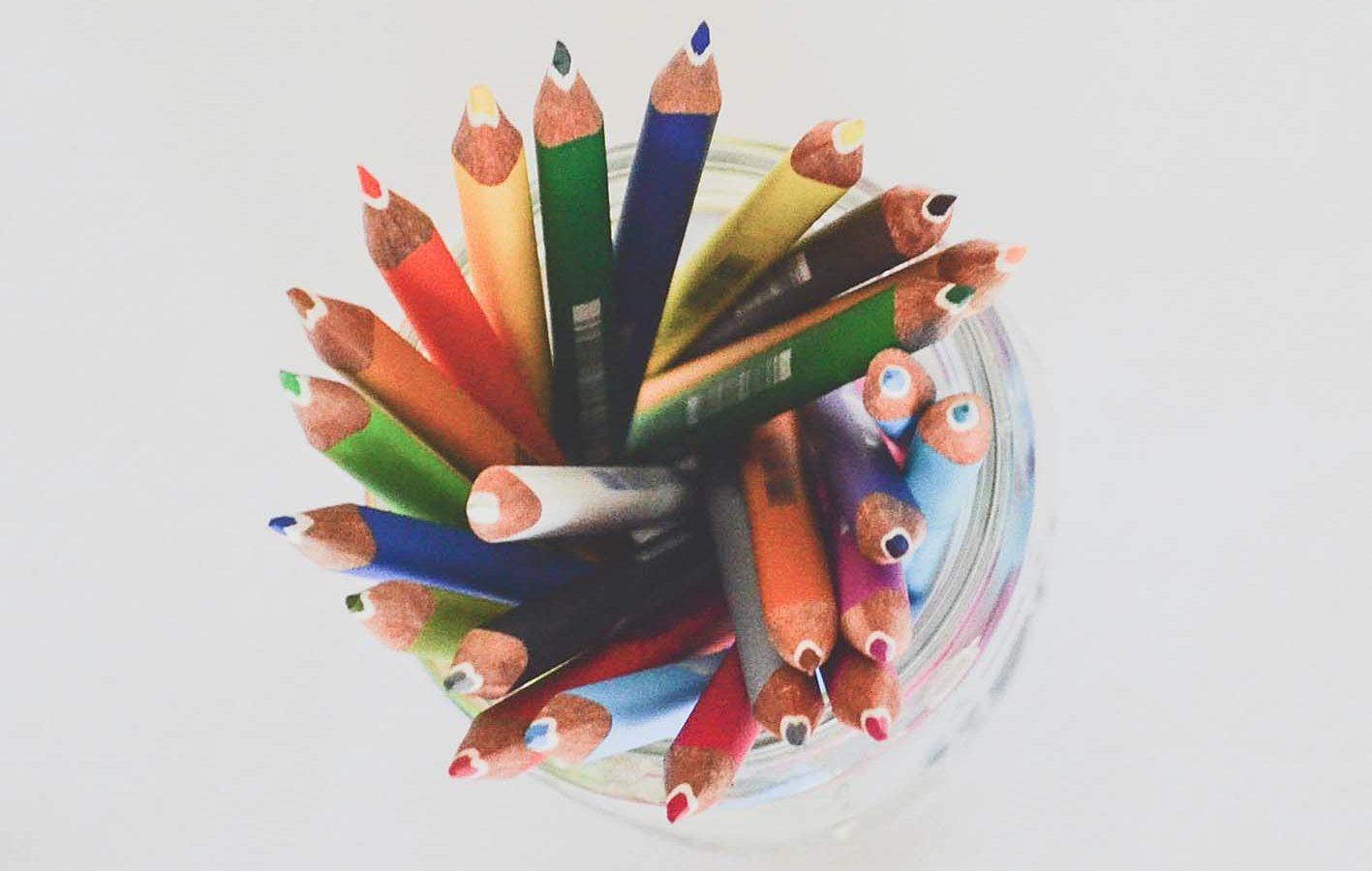 Different coloured pencils in a glass jar, viewed from above