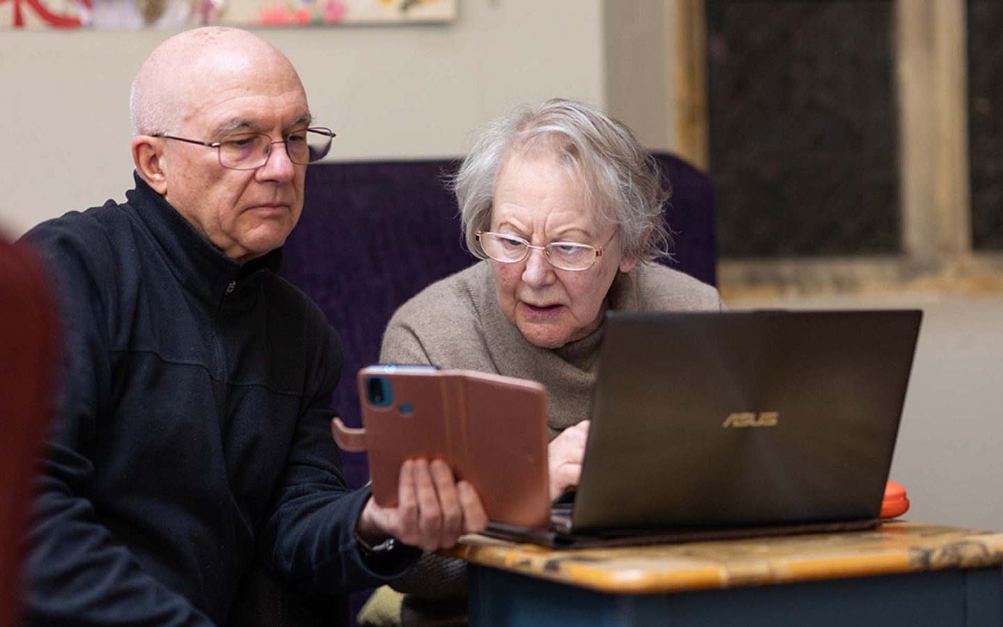 Elderly person receiving support using smart phone and laptop