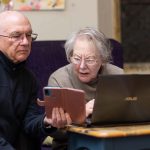 Elderly person receiving support using smart phone and laptop