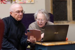 Elderly person receiving support using smart phone and laptop