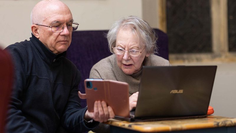 Elderly person receiving support using smart phone and laptop