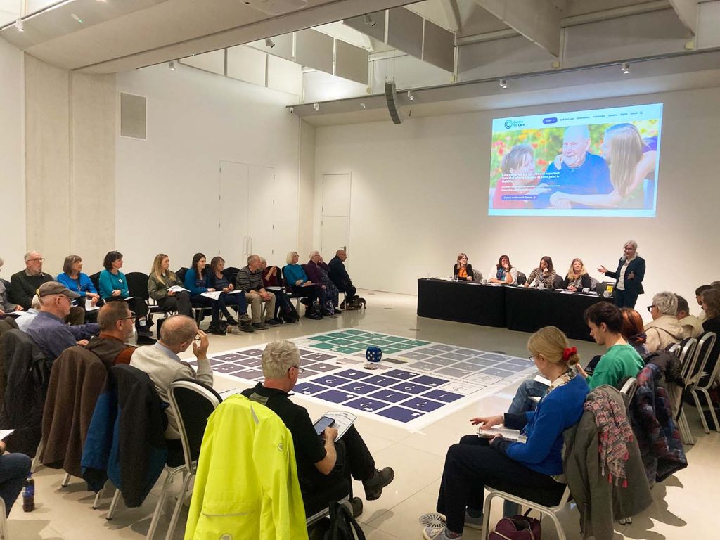 People sitting in chair around large board game on the floor