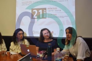 Three people presenting research in front of a projected screen