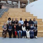 14 students sitting on indoor steps