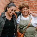 two people with arms around each other smiling