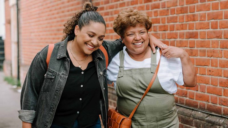 two people with arms around each other smiling