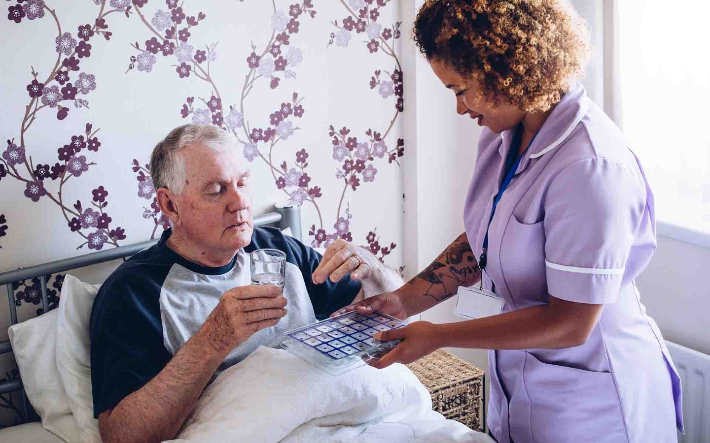 Member of care home staff helping patient with medication