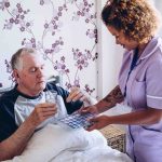 Member of care home staff helping patient with medication