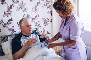 Member of care home staff helping patient with medication