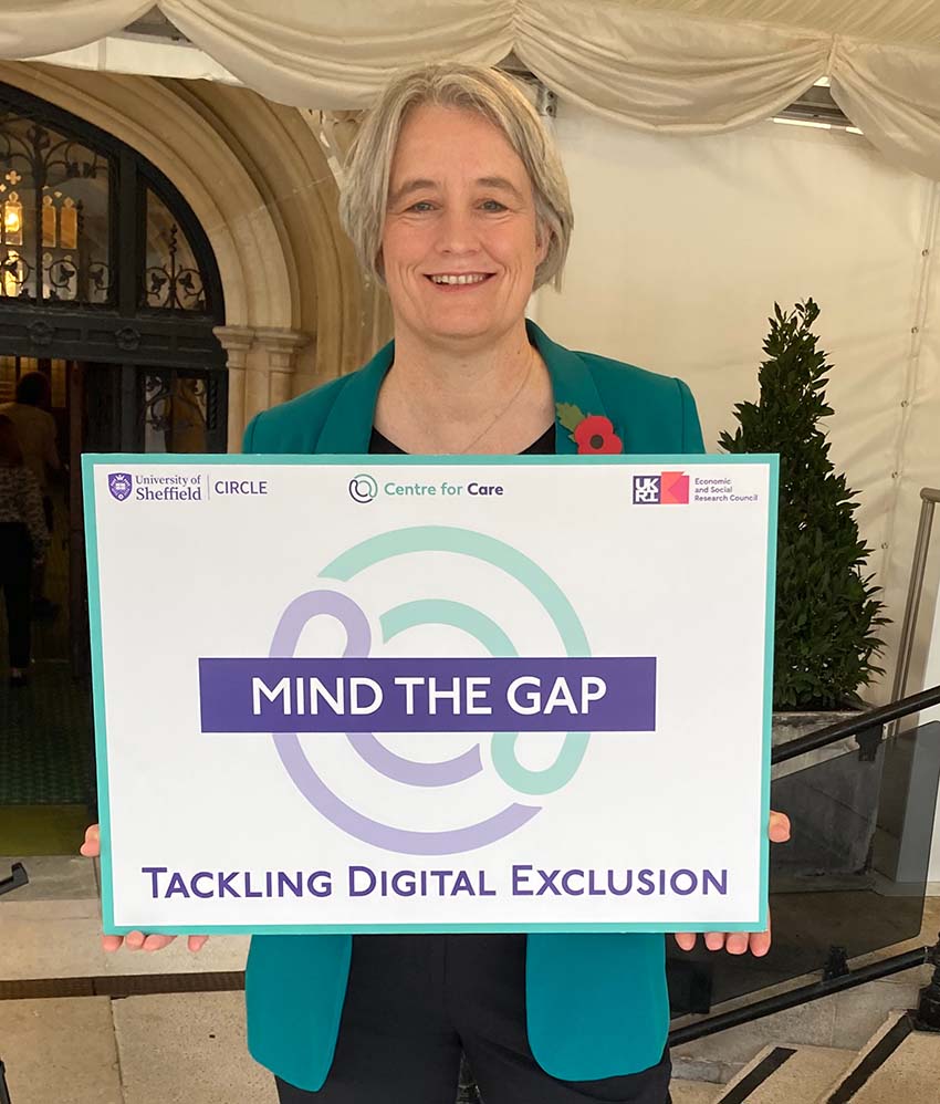 Claire Young MP holding board which says 'Mind the Gap: Tackling Digital Exclusion'