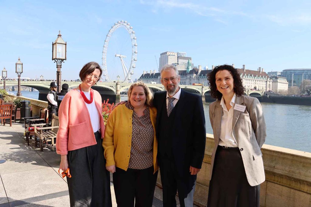 people by the side of the Thames river outside Parliament
