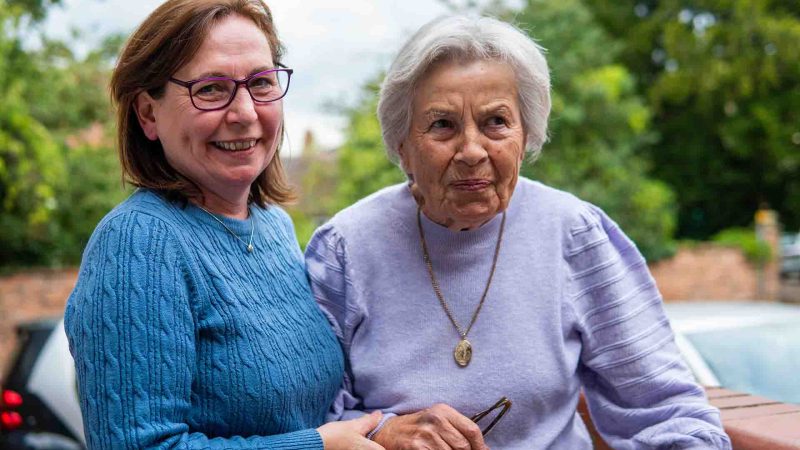 middle-aged person helping older person