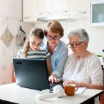 three people of different generations using a laptop