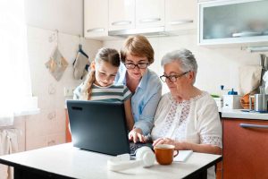 three people of different generations using a laptop