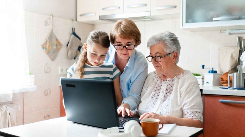three people of different generations using a laptop