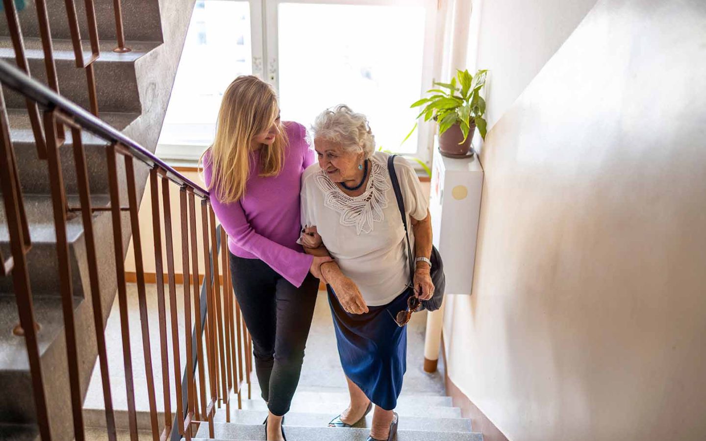 person helping older person climb stairs in house