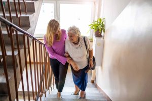 person helping older person climb stairs in house