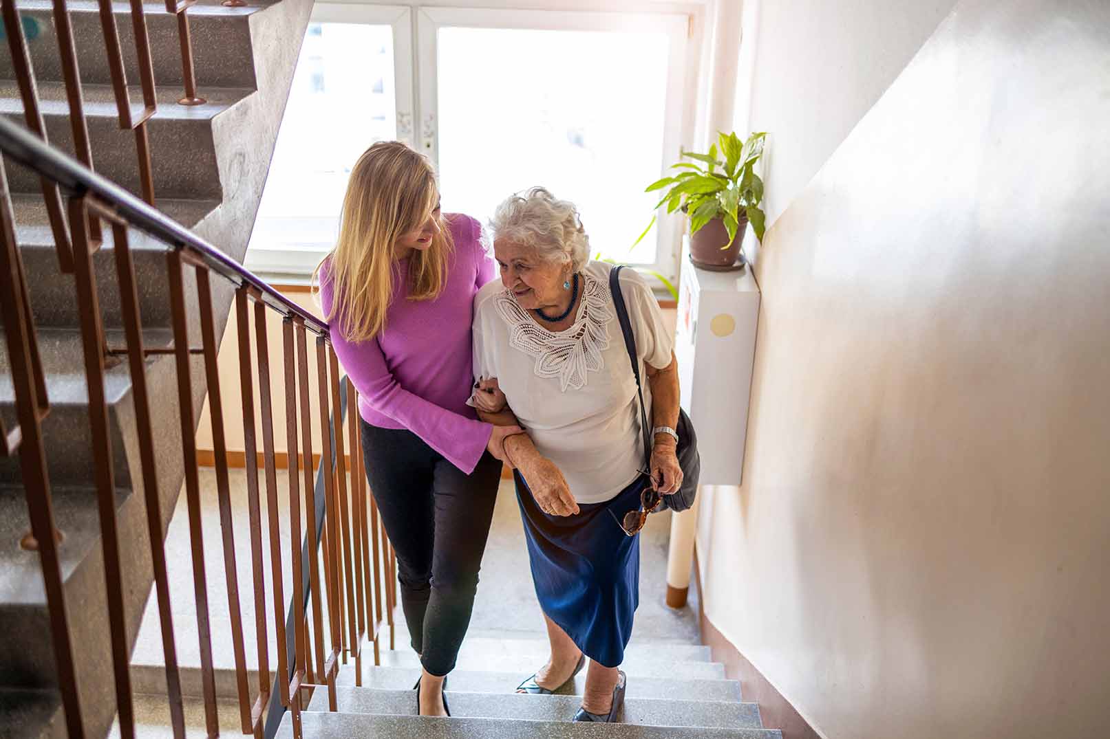 person helping older person climb stairs in house