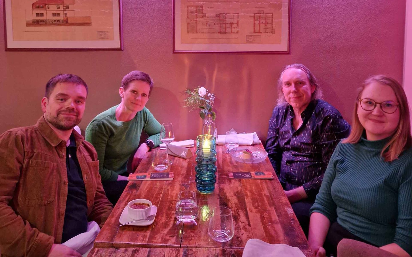 Four people sitting at a dining table in a room lit by purple lighting