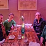 Four people sitting at a dining table in a room lit by purple lighting
