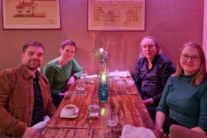Four people sitting at a dining table in a room lit by purple lighting