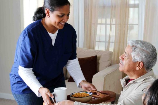 A care worker handing a meal to a care home resident