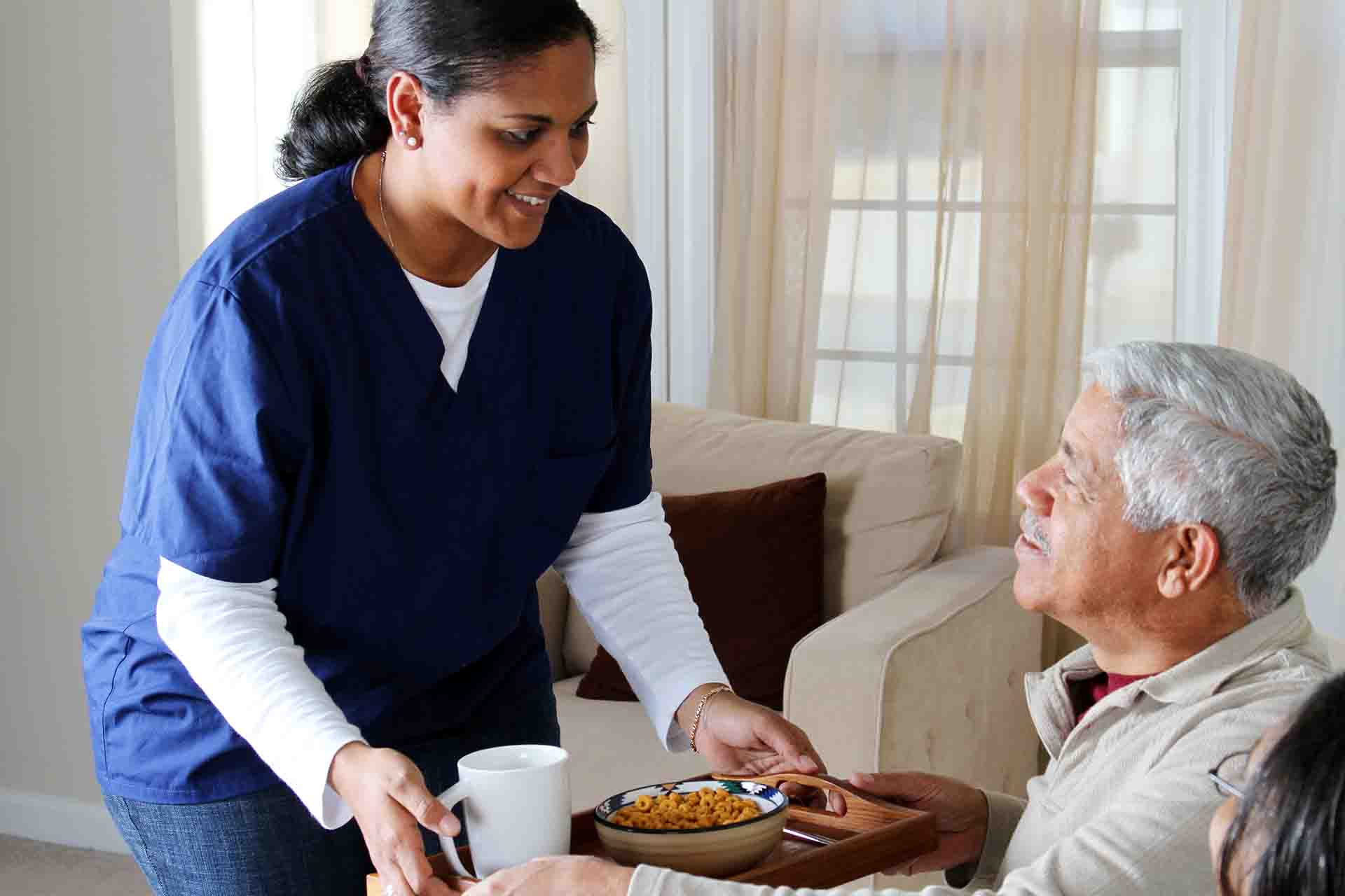 A care worker handing a meal to a care home resident