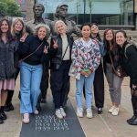 Summer School participants pose next to WOmen of Steel statue in Sheffield