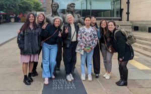 Summer School participants pose next to WOmen of Steel statue in Sheffield