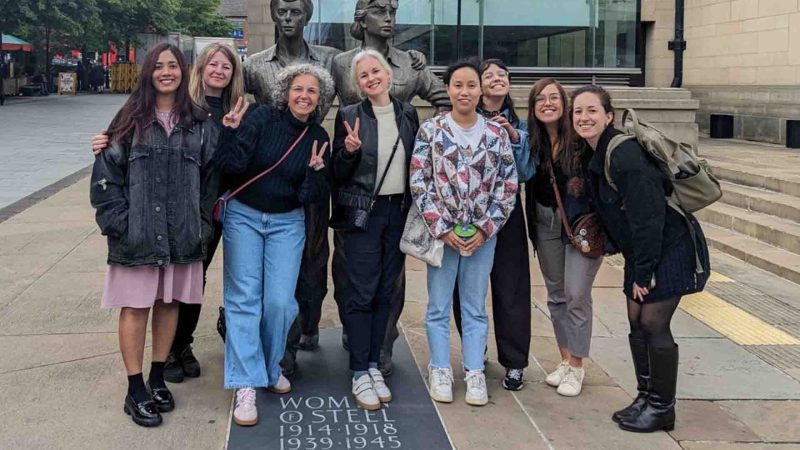 Summer School participants pose next to WOmen of Steel statue in Sheffield