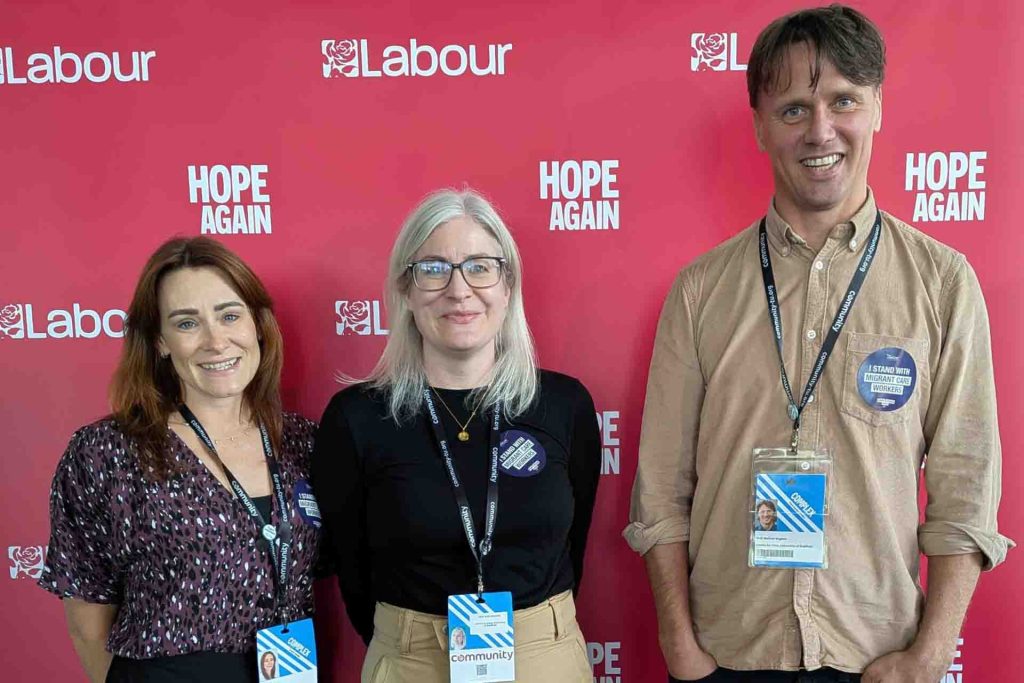 Fay Benskin, Kate Hamblin and Nathan Hughes smiing in front of Labour Party branded banner